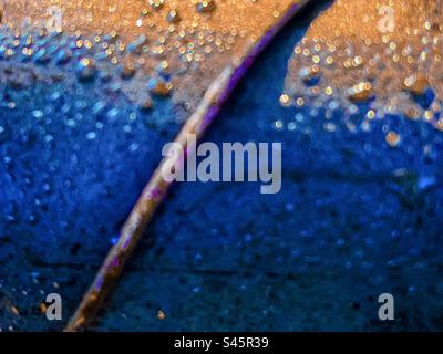 Close-up, abstract, full frame, backgrounds shot of rain droplets on metal surface in sunlight. Selective focus. Blue and golden colors. Texture. Stock Photo