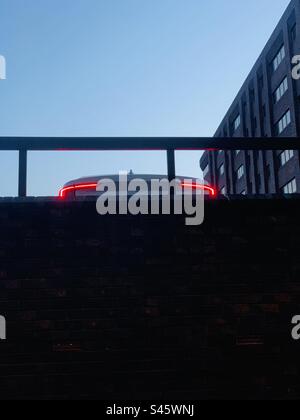 Brake lights on an electric car in a city car park at dusk - ev car lights city parking copy space Stock Photo