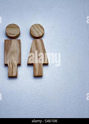 Wooden man and woman toilet signs on white wall with copy space. Restroom icon, minimal style. Stock Photo