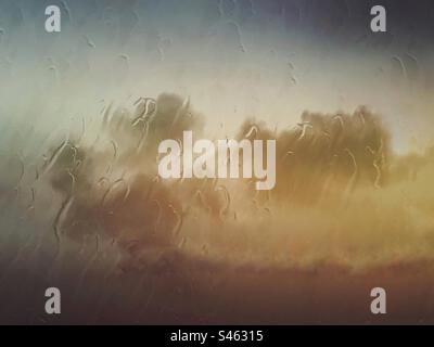 Clouds and sky background with rain and raindrops on a glass window- wet weather sky cloud backdrop Stock Photo