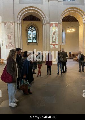 Visitors look on at the wall paintings in the nave at St Albans Cathedral, England. Stock Photo