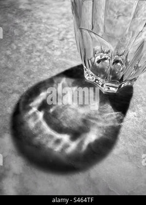 Shadow of an empty drinking glass on a marble table top. Photo ©️ COLIN HOSKINS. Stock Photo