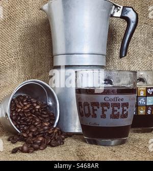 Coffee beans, black coffee and stovetop pot on sackcloth Stock Photo