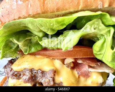 Burger in a bun with melted cheese, bacon and tomato Stock Photo