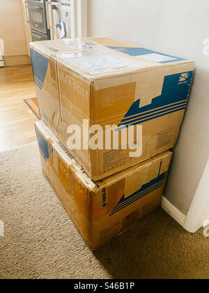 Large boxes, packages received from a courier stacked against a wall. Stock Photo