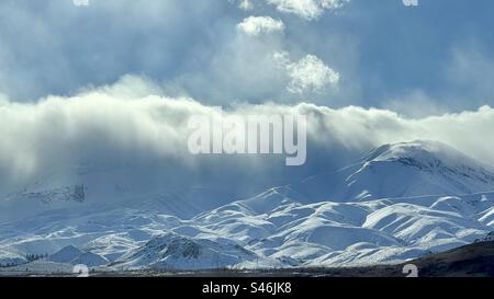 Low winter clouds rolling in over snow covered mountains Stock Photo