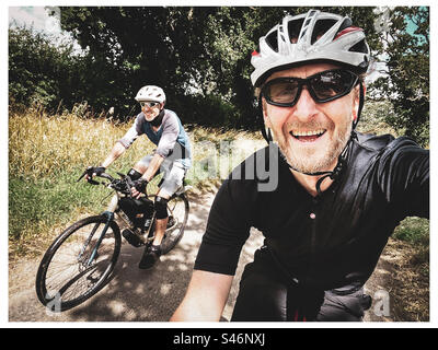 Two friends enjoy a bike packing trip in good weather in Norfolk UK in the summer Stock Photo