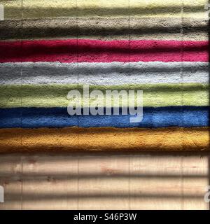Colored stripes on a rug with sunlight coming through window blinds, creating an additional pattern; two layers of abstract stripes for a useful graphic background Stock Photo