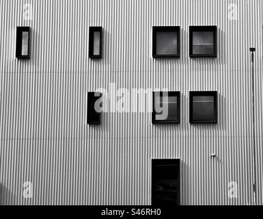 Abstract if black framed rectangular windows in corrugated metal wall on modern building in Bolton Stock Photo