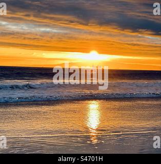 Sun setting over Palms Verdes Peninsula and offshore oil drilling platform as seen from Sunset Beach (Huntington Beach, California). Stock Photo