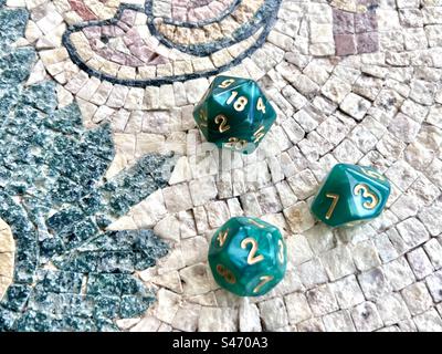 Role-play dice  - 3 green dice including d20 on a mosaic table Stock Photo