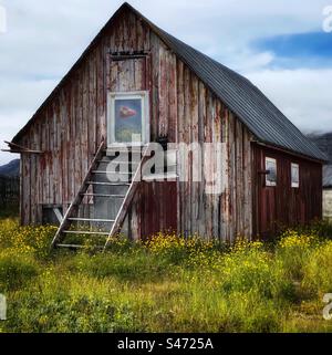 An abandoned barn in Greenland with the national flag reflected in the window Stock Photo