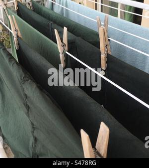 Bucato steso all'aria di varie tonalità di verde. Mollette di legno.  Laundry hanging in the air in various shades of green. Wooden clothespins. Stock Photo