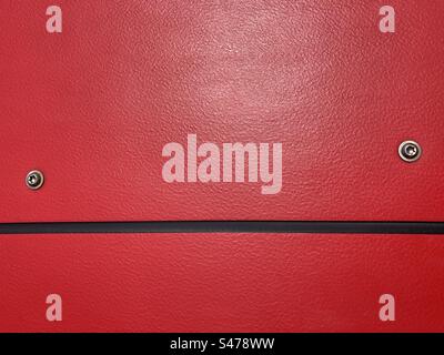 red plastic surface with black horizontal line and two metal screw heads Stock Photo