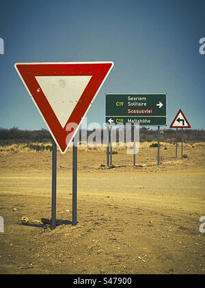 A red warning triangle sign on a gravel road in Namibia Stock Photo