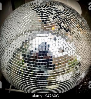 Pixelated reflection of the photographer in a silver mirror ball. Stock Photo
