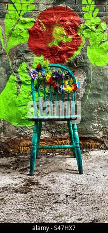 Closeup of a green antique chair adorned with artificial flowers. Stock Photo