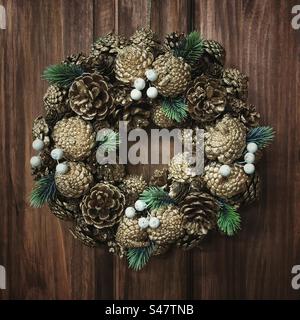 Luxury Christmas door wreath with pine cones and spruce leaves in a dark wood background and square frame Stock Photo