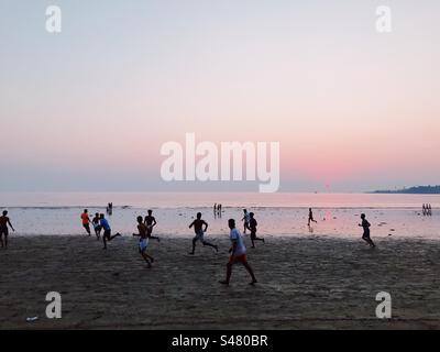 People playing football on Versova beach in Mumbai during sunset Stock Photo