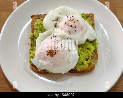 Close up view of two poached eggs on avocado toast with black pepper Stock Photo