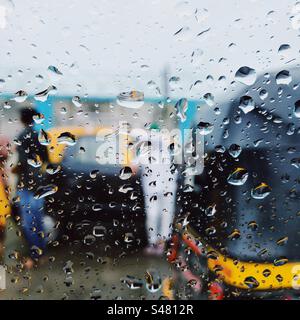 A taxi and an autorickshaw seen through a car window with rain droplets on it Stock Photo