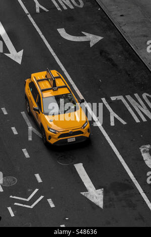 Aerial view above a New York yellow taxi on an empty street with directional arrows and road markings in New York City with copy space Stock Photo