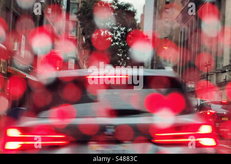 Red brake and stop lights reflected in rain drops on car windscreen, caught in traffic, Manhattan New York Stock Photo