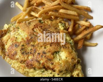 Omelette made with cheese and herbs, served with crunchy, golden, shoestring fries. Stock Photo