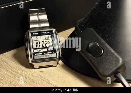 Silver square Casio WaveCeptor Watch on a black side table lamp switch. Stock Photo
