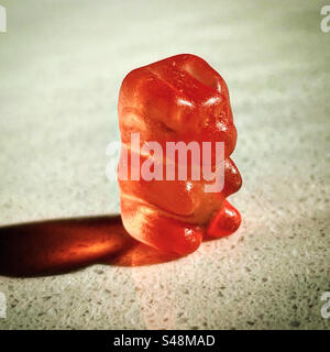 single gummy bear on a kitchen or store candy store under the sun with orange translucent transparent chewy texture Stock Photo