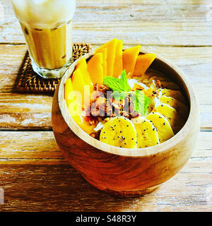 Breakfast of a tropical smoothie bowl with banana and mango and an iced coffee in Bali Indonesia Stock Photo