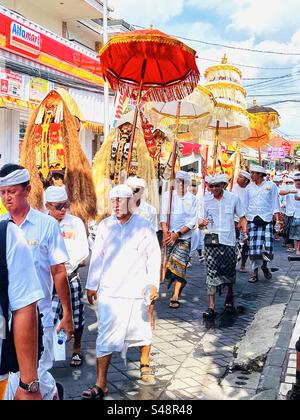 Traditional ceremony procession in Bali Indonesia on the street with umbrellas and masks Stock Photo
