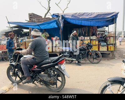 Motorbikes passing by shops selling Indian snacks in a small town in northern India Stock Photo
