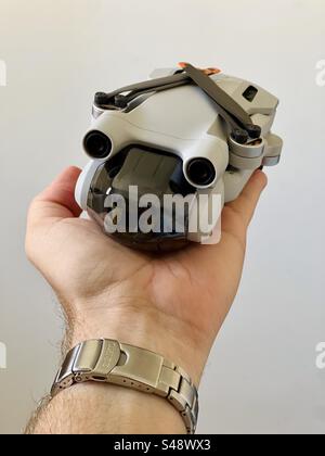 Studio shot of a small DJI Mini Pro 3 or 4 drone on a hand on white background. Stock Photo