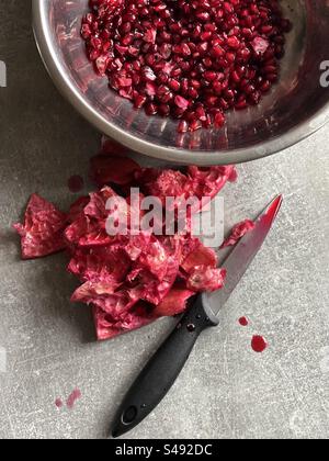 peeled pomegranate in a bowl and knife Stock Photo