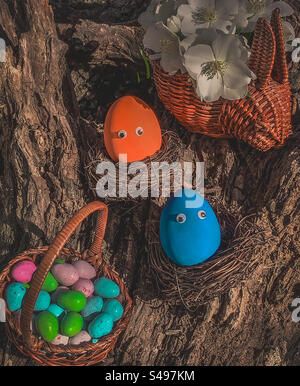 Easter eggs in nests & basket on tree stump, with blossom Stock Photo
