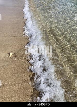 Seashore photo of tide coming in onto the beach and waves lapping on sand at shoreline Stock Photo