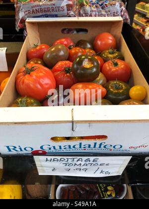 Heritage tomatoes varieties priced up for sale at a local grocers shop Stock Photo