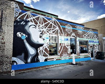 Wall mural of woman in downtown area of Loveland, Colorado, USA.  Door and windows on textured, brick wall. Stock Photo