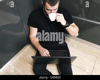 Young man drinking coffee and using laptop at home Stock Photo