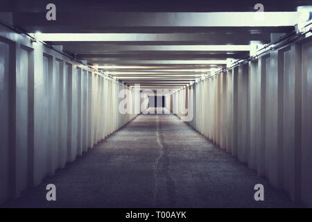 Highway tunnel. Interior of an urban tunnel without traffic. Pedestrian crossing under the road. A long concrete tunnel with lanterns in the city unde Stock Photo