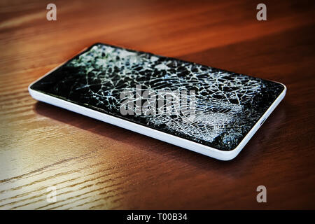 Modern frameless Smartphone with broken screen on the wooden table Stock Photo