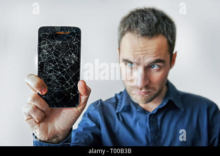Sad man holds broken smartphone. Screen broken phone. Not working phone Stock Photo
