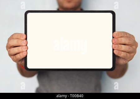Close up of a digital tablet in man's hands. An upper half shot of a man holding a tablet with white screen in hands. Person on the isolated backgroun Stock Photo