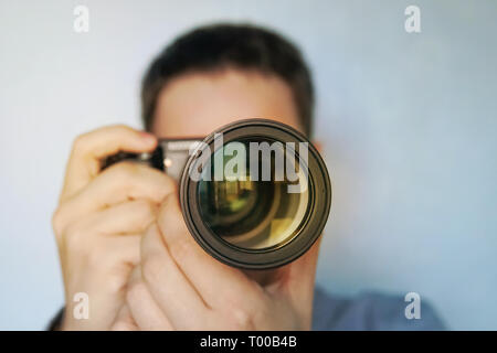 Portrait of a stylish photographer and hat standing with camera on the blue background. young photographer paparazzi looking at the camera. the moment Stock Photo