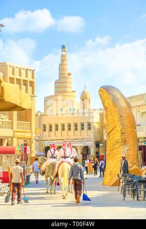 Doha, Qatar - February 20, 2019: two police officers riding white Arabian horses at Souq Waqif. Fanar Islamic Cultural Center with Spiral Mosque and Stock Photo