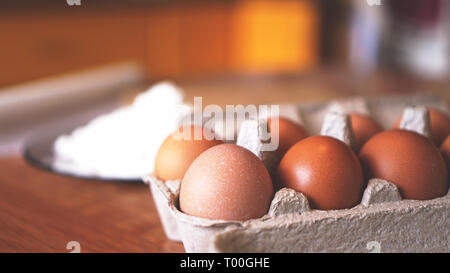 Ingredients for baking homemade bread. Eggs, flour. Wooden background, side view. Soft focus and light Stock Photo