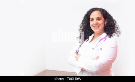 Female latin female doctor standing looking at the camera in her office with stethoscope on her neck with her arms crossed on white background Stock Photo