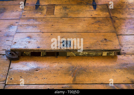 Partially opened hemlock wood plank trap door in dining room leading to crawlspace inside an old circa 1760 Canadiana fieldstone cottage style house Stock Photo