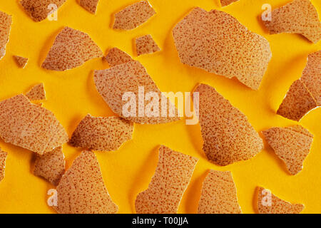 Broken chichen eggshell close up on a colored background ,brown surface with dark brown spots , abstract effect Stock Photo